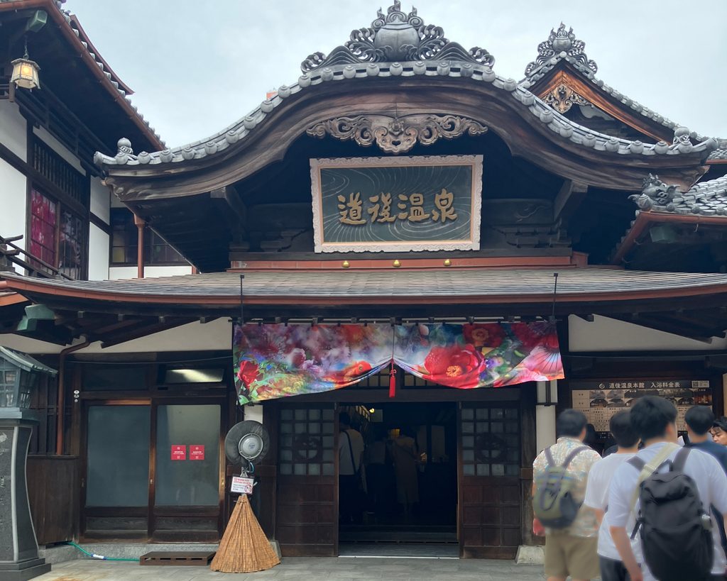 道後温泉本館の正面玄関と、入口に飾られた色鮮やかな暖簾